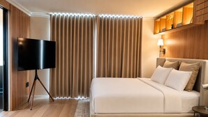 A modern hotel room with a large bed, a flat-screen TV, wooden paneling, and a ceiling light. - Residence L'heritage Hipólito Taine by Bluebay (Mexico City)