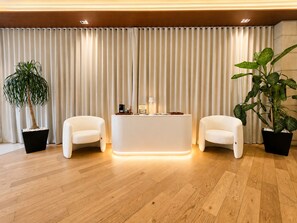 A room with a wooden floor, two white armchairs, a central table with a lamp, and two potted plants. - Residence L'heritage Hipólito Taine by Bluebay (Mexico City)