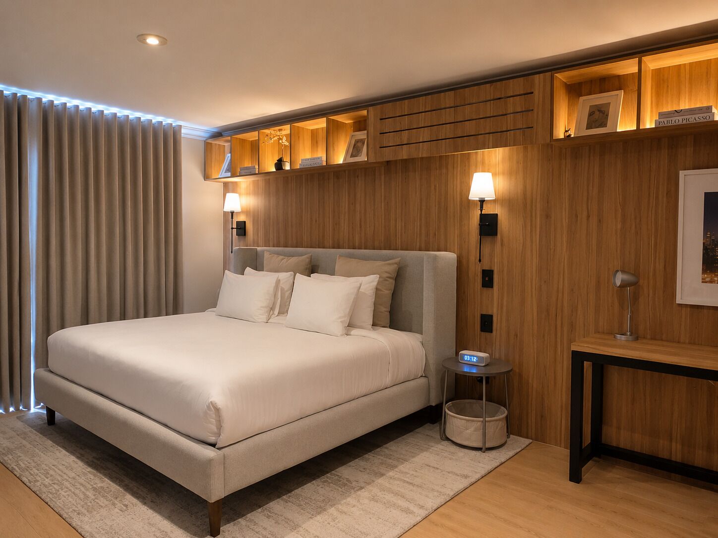 A modern hotel room with a large bed, wooden paneling, a nightstand, a lamp, and a framed picture on the wall.