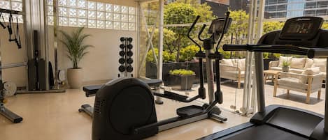A gym with exercise equipment, a treadmill, and a view of the outdoors.