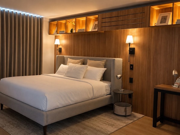 Ett modernt hotellrum med en stor säng, träpanel och inbyggda hyllor med inramade bilder.