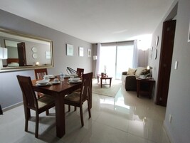 A dining area with a table set for four, a sofa, and a coffee table.