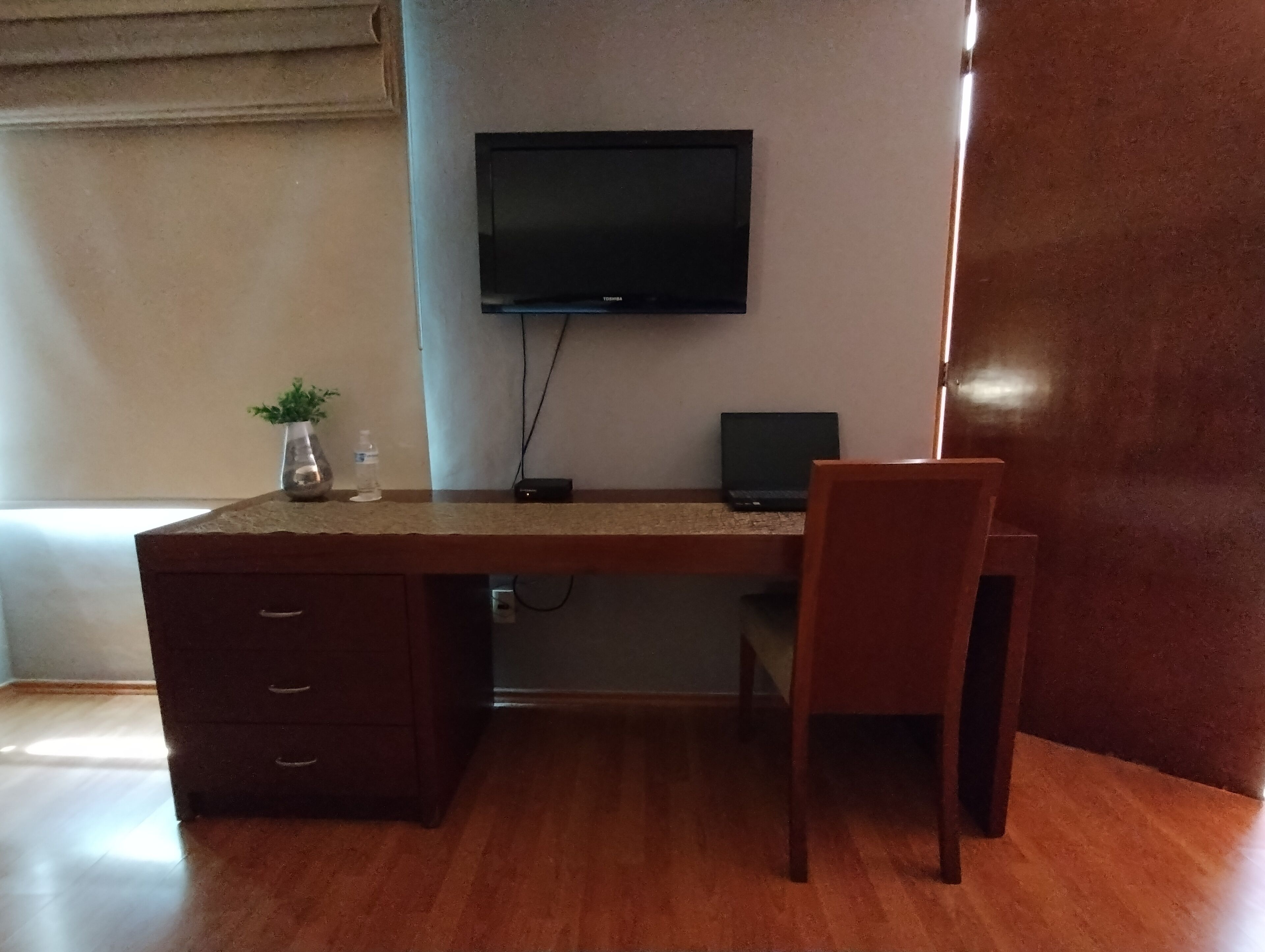 Un escritorio de madera con una televisión de pantalla plana, una computadora portátil y una silla.
