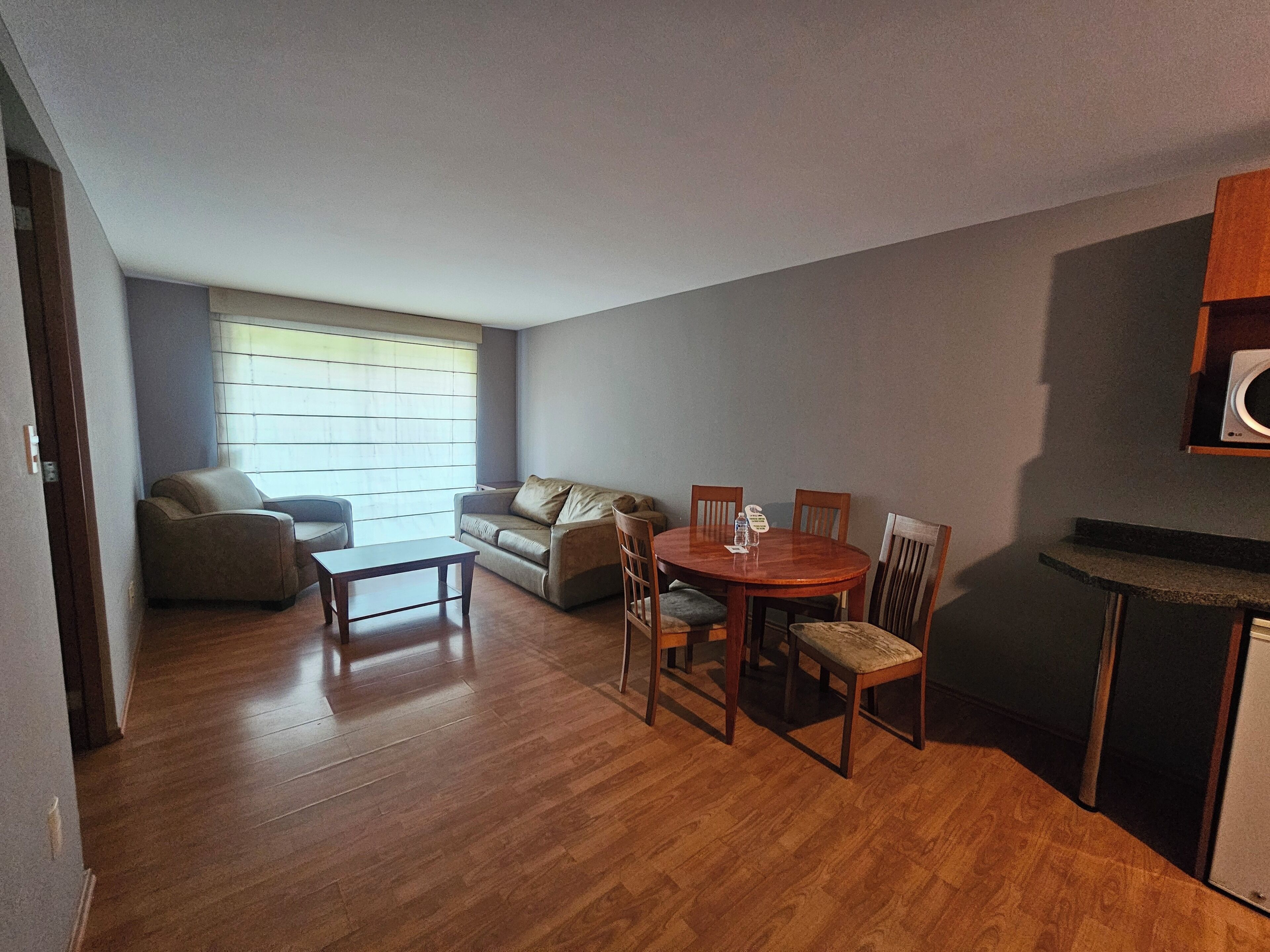 Un espacio habitable compacto con una mesa de comedor, sillas, un sofá y una pequeña kitchenette.