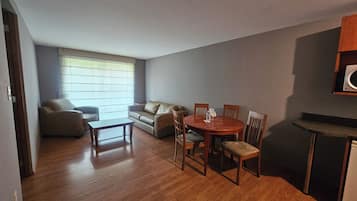 Un espacio habitable compacto con una mesa de comedor, sillas, un sofá y una pequeña kitchenette.