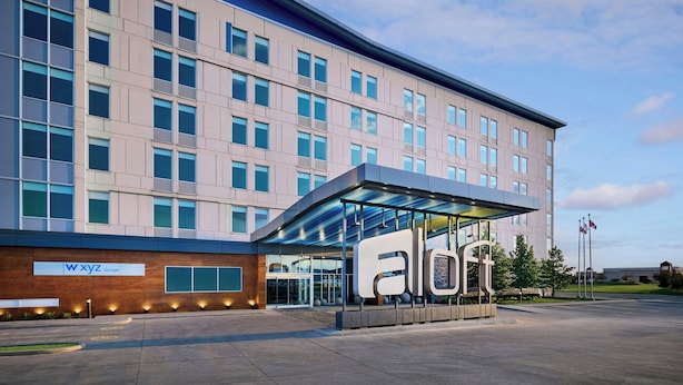 A modern hotel building with a large entrance, a covered area with the logo 'a l o f t', and a sign for 'WXYZ Lounge'.