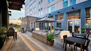 An outdoor patio area with a sofa, chairs, a table, and potted plants.