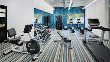 A gym with various exercise equipment, including treadmills, an elliptical, and free weights.
