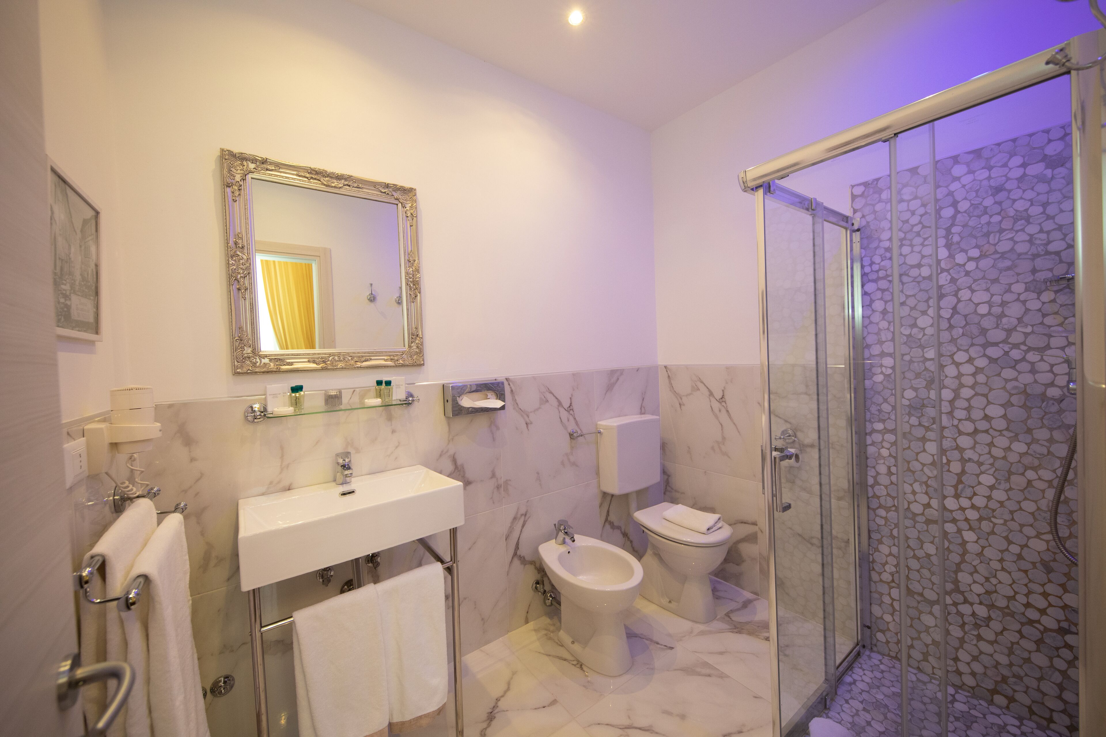 Une salle de bain moderne avec un lavabo en marbre, un bidet, des toilettes et une douche à parois de verre.