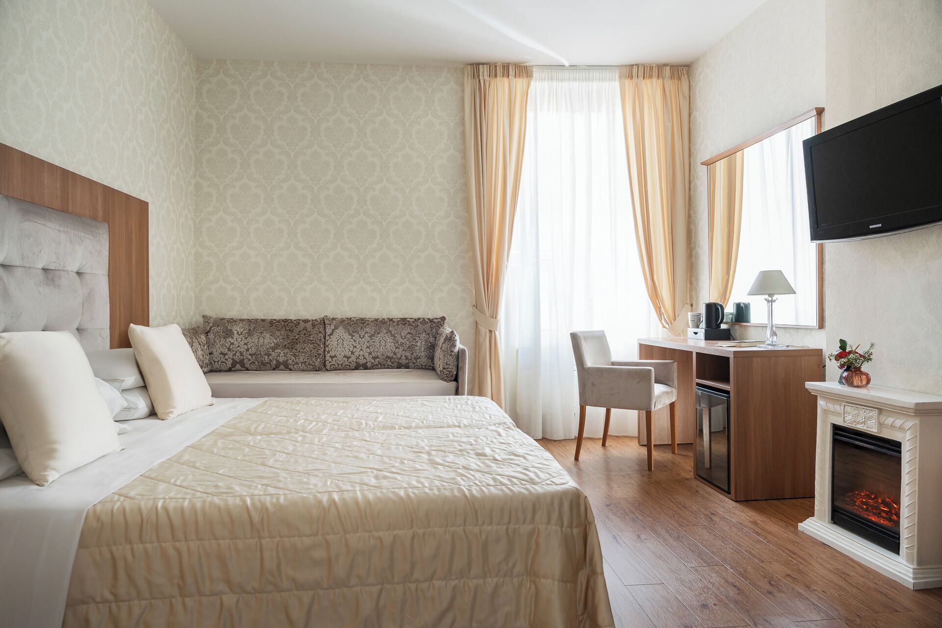Une chambre d’hôtel équipée d’un lit, d’un bureau, d’une chaise, d’une télévision et d’une cheminée.