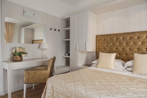 Een hotelkamer met een bed, een bureau met stoel, een spiegel en een kledingkast.
