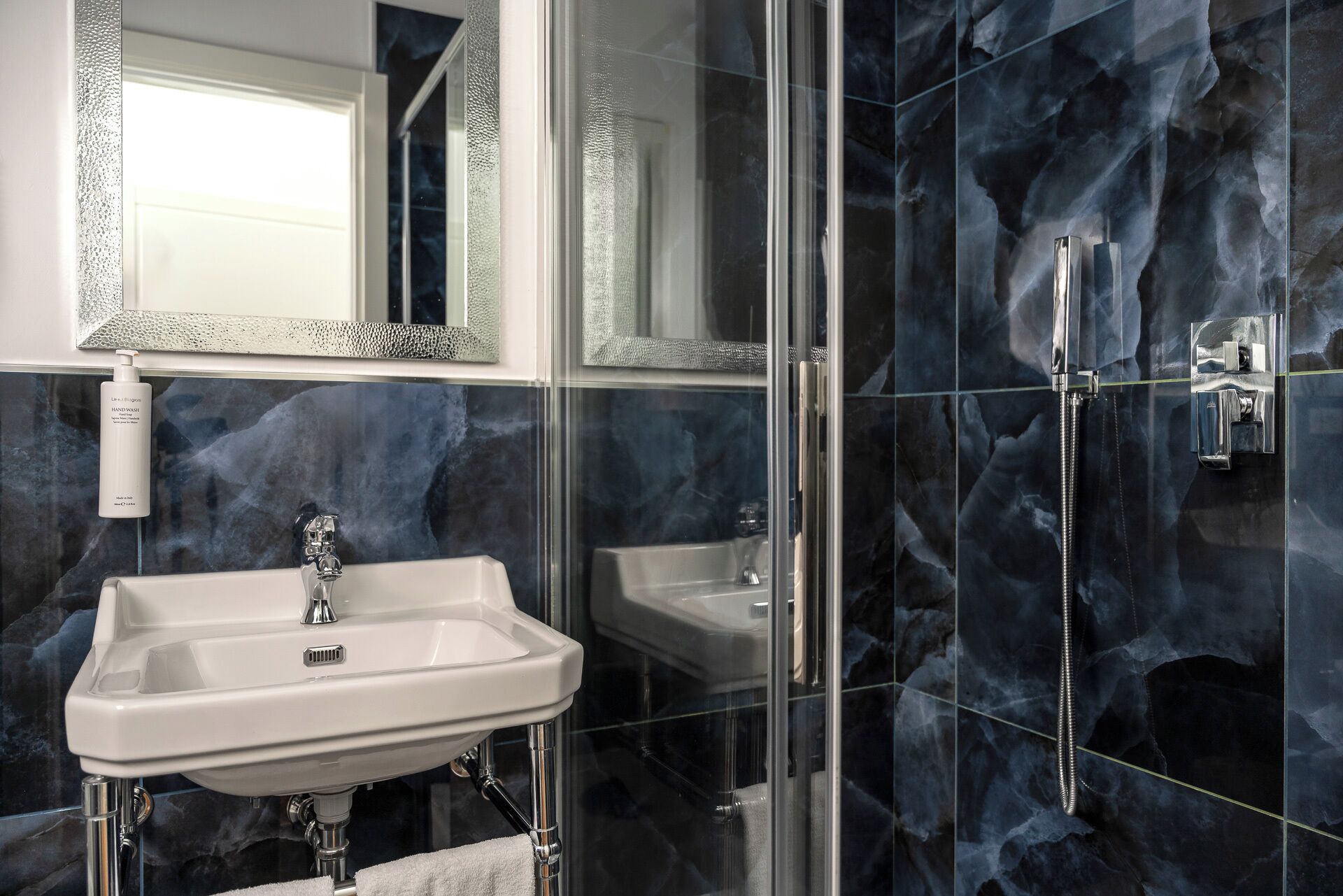 A bathroom with a white sink, a mirror, and a shower with a glass door.
