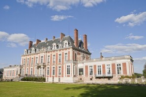 Een groot, historisch gebouw met meerdere schoorstenen en een symmetrische gevel.