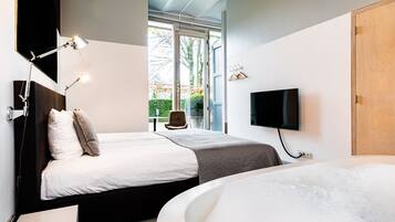 Une chambre d’hôtel moderne avec deux lits, une grande baignoire, une télévision et une vue sur l’extérieur.