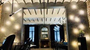 Un intérieur moderne avec une cheminée, un plancher en bois et des chaises noires disposées autour d’une table.