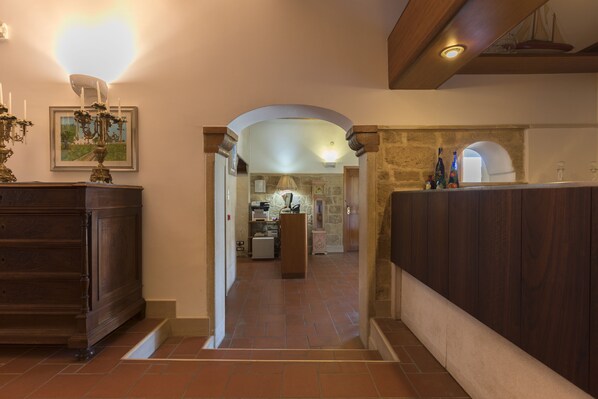 A hallway with a wooden dresser, a framed picture, and a stone wall. - Masseria Sant'Anna (Bari)