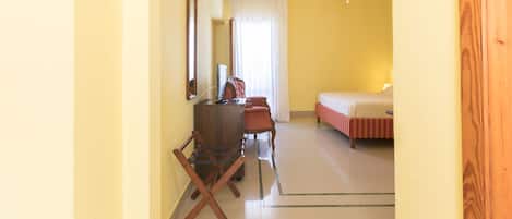 A hotel room with a bed, a desk with a computer, a chair, and a mirror.