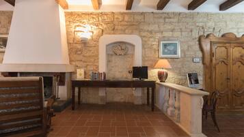 A stone fireplace with a mantel, a wooden bench, a table with books, and a wooden door.