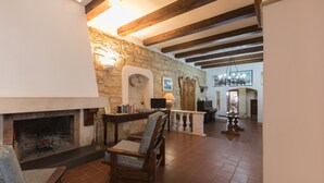 A spacious living room with a stone fireplace, wooden beams, and a comfortable seating area.