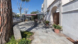 A courtyard with stone flooring, a covered seating area, and potted plants.