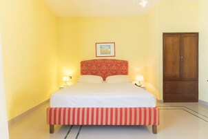 Habitación de hotel con cama, lámparas de noche, armario de madera y un cuadro en la pared.