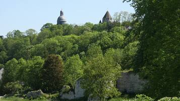A lush green landscape with a prominent white stone wall and a small tower.