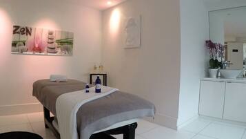 Relax in a serene space with a massage table, sink, and soothing artwork.