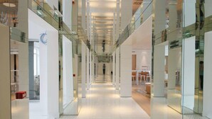 A modern interior with glass railings, a central walkway, and a person walking. - Le Cesar Hotel (Provins)