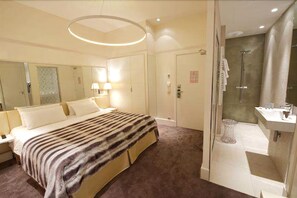 A hotel room with a large bed, a bathroom with a shower, and a mirror. - Le Cesar Hotel (Provins)