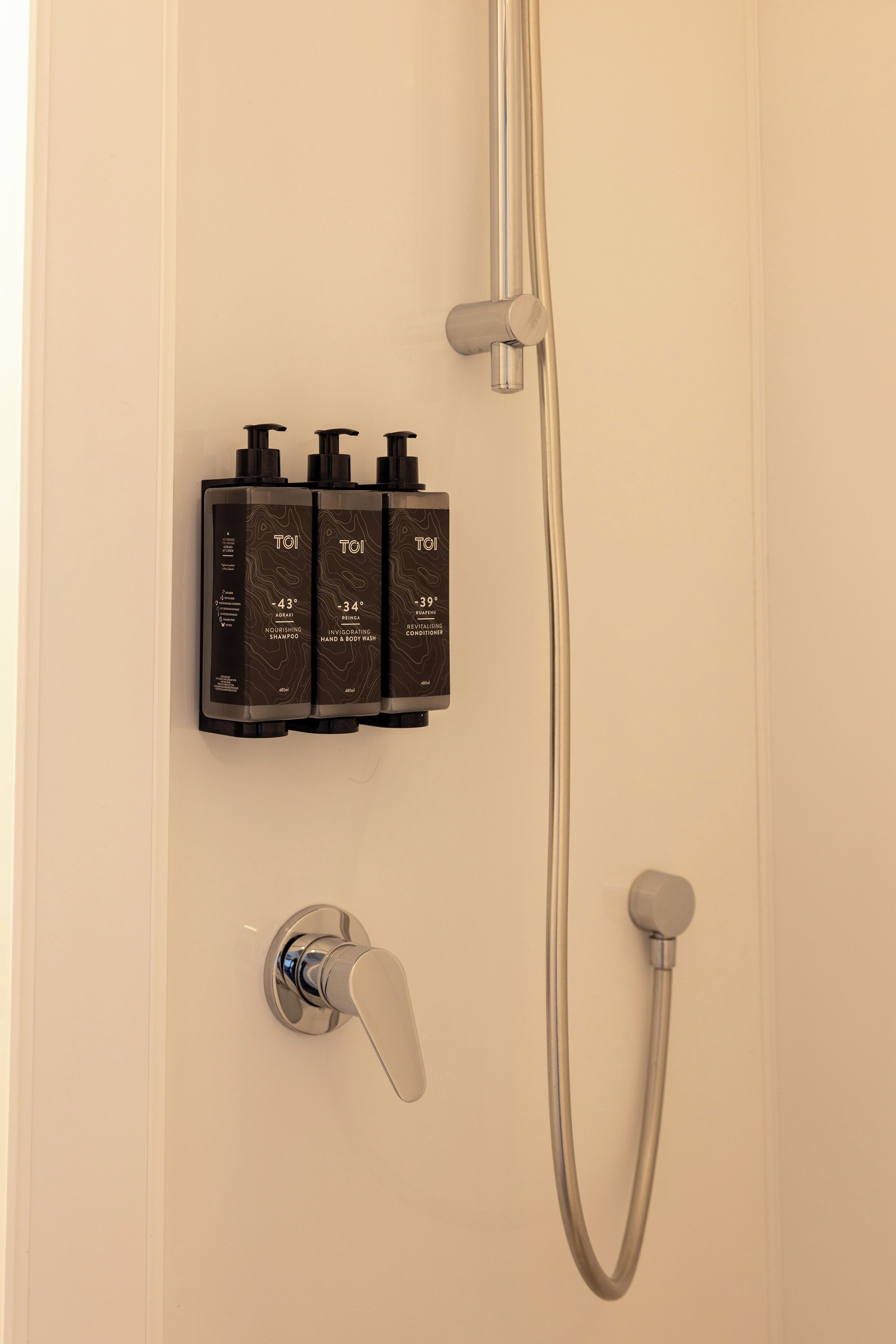 A bathroom with a shower, a faucet, and a set of toiletries.