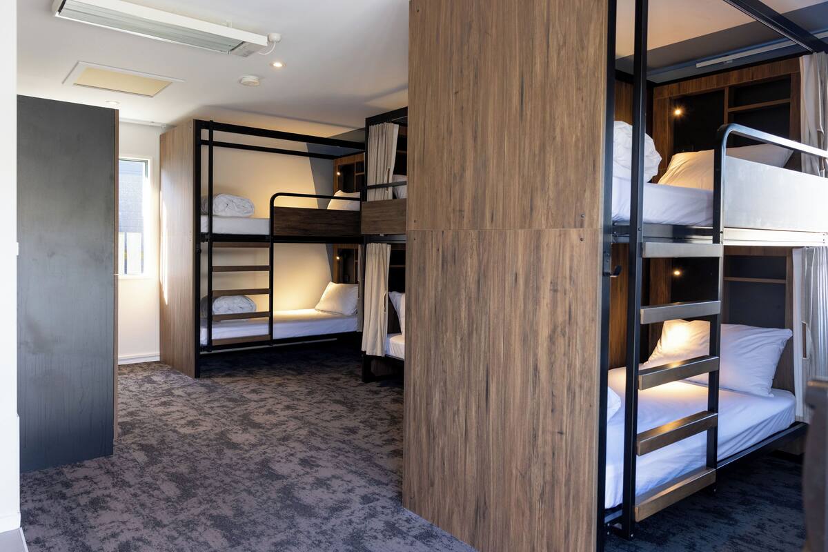 A compact room with bunk beds, a wooden partition, and a carpeted floor.
