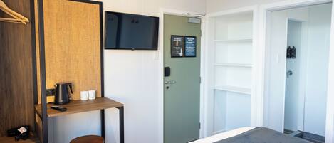 A hotel room with a bed, a desk with a chair, a television, and a door leading to a bathroom.