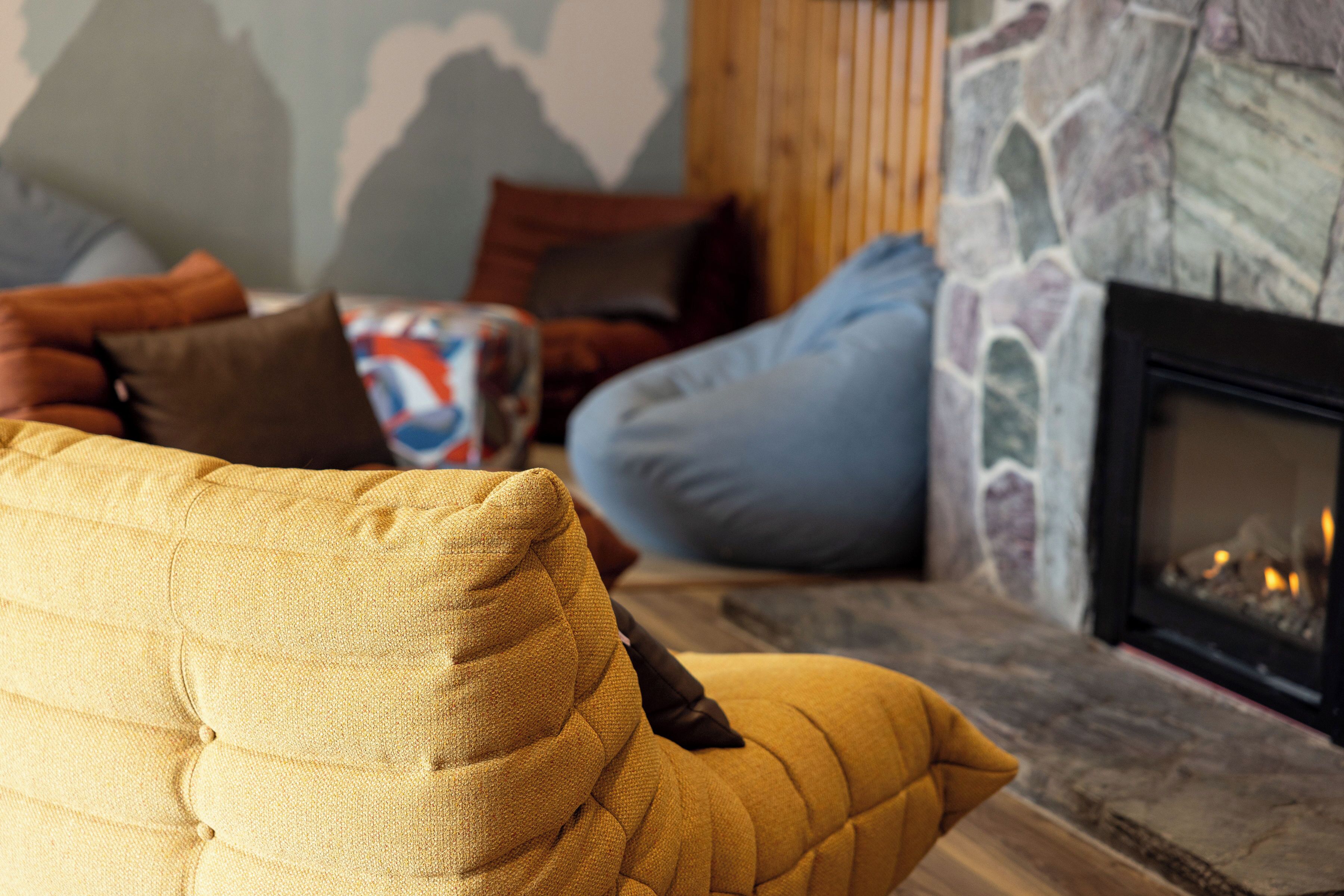 A cozy living room with a fireplace, a stone wall, and various cushions.