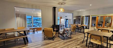 Enjoy meals in a spacious dining area with a wood-burning stove and large windows offering views of the outdoors.