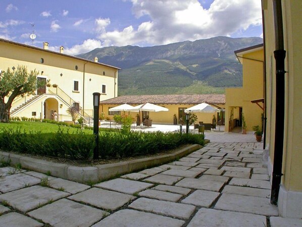 A courtyard with stone paving, outdoor seating, and a mountain backdrop.