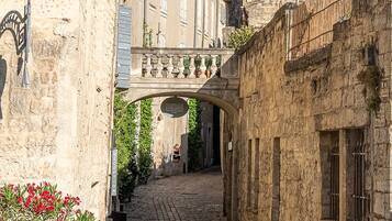 A narrow cobblestone street flanked by historic stone buildings with a bridge overhead.