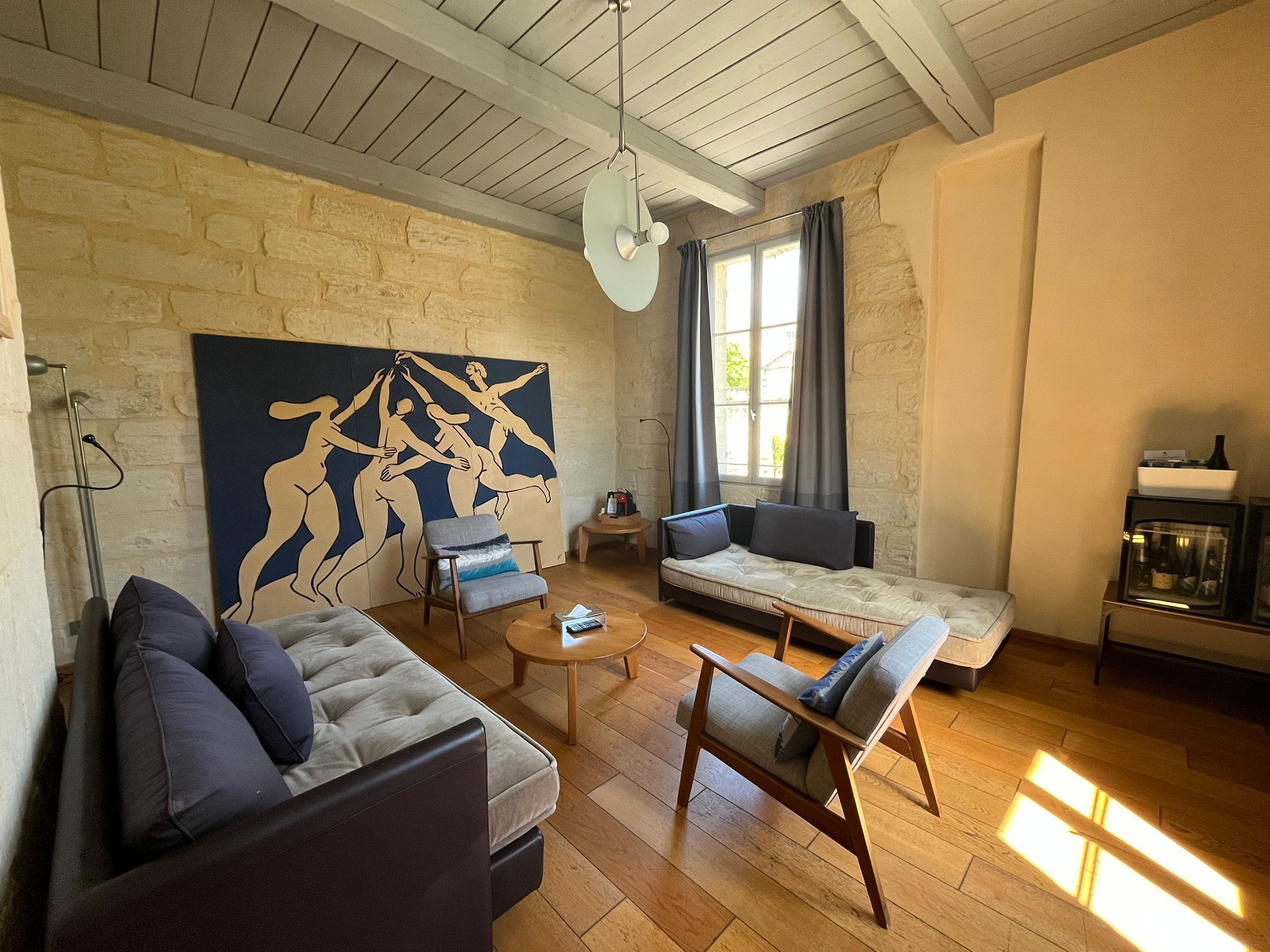 Een woonkamer met een bank, fauteuils, een salontafel, een schilderij en een open haard.