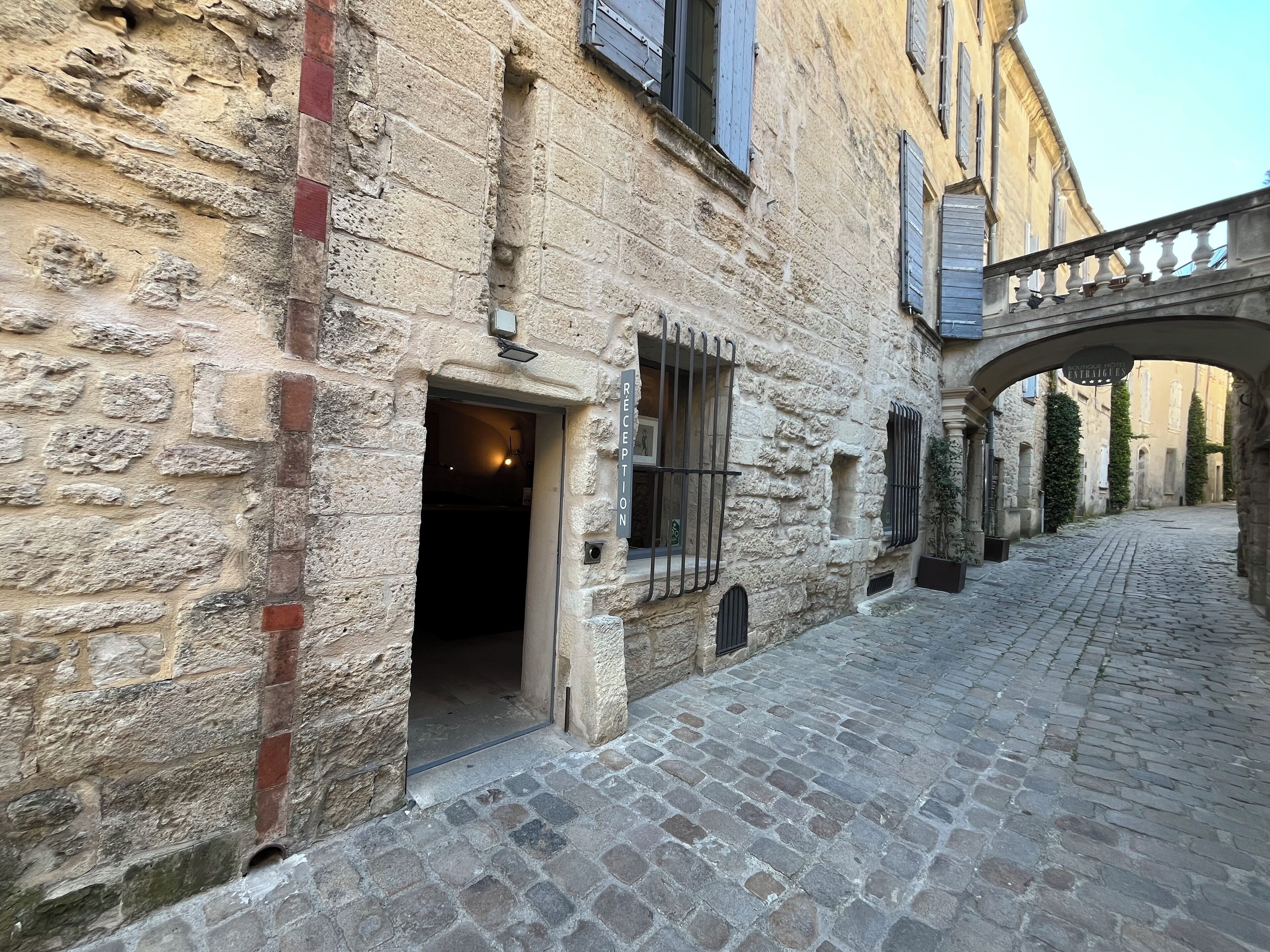A stone building with a reception area, a cobblestone street, and a covered passageway.
