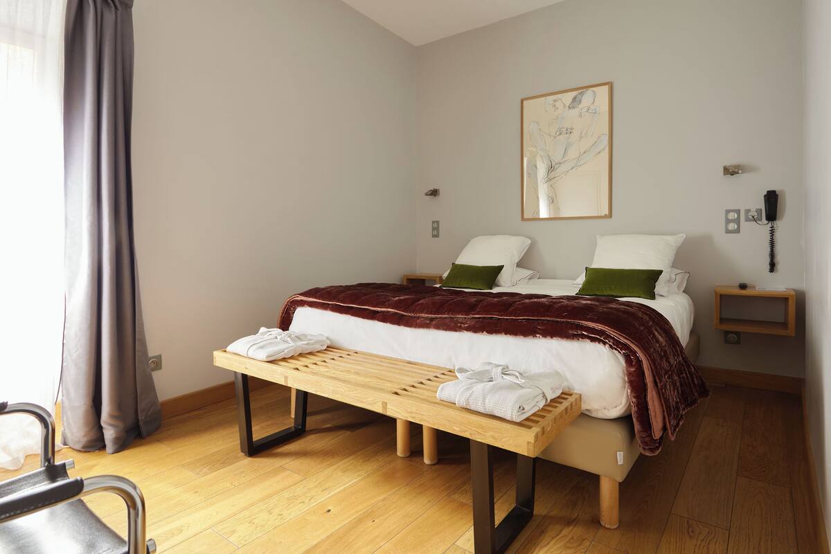 A neatly arranged bedroom with a bed, bedside tables, a bench, and a chair.