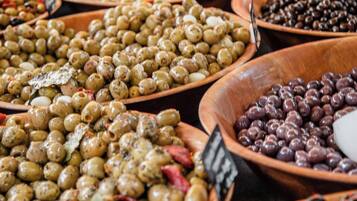 A variety of olives in wooden bowls, some labeled with prices.