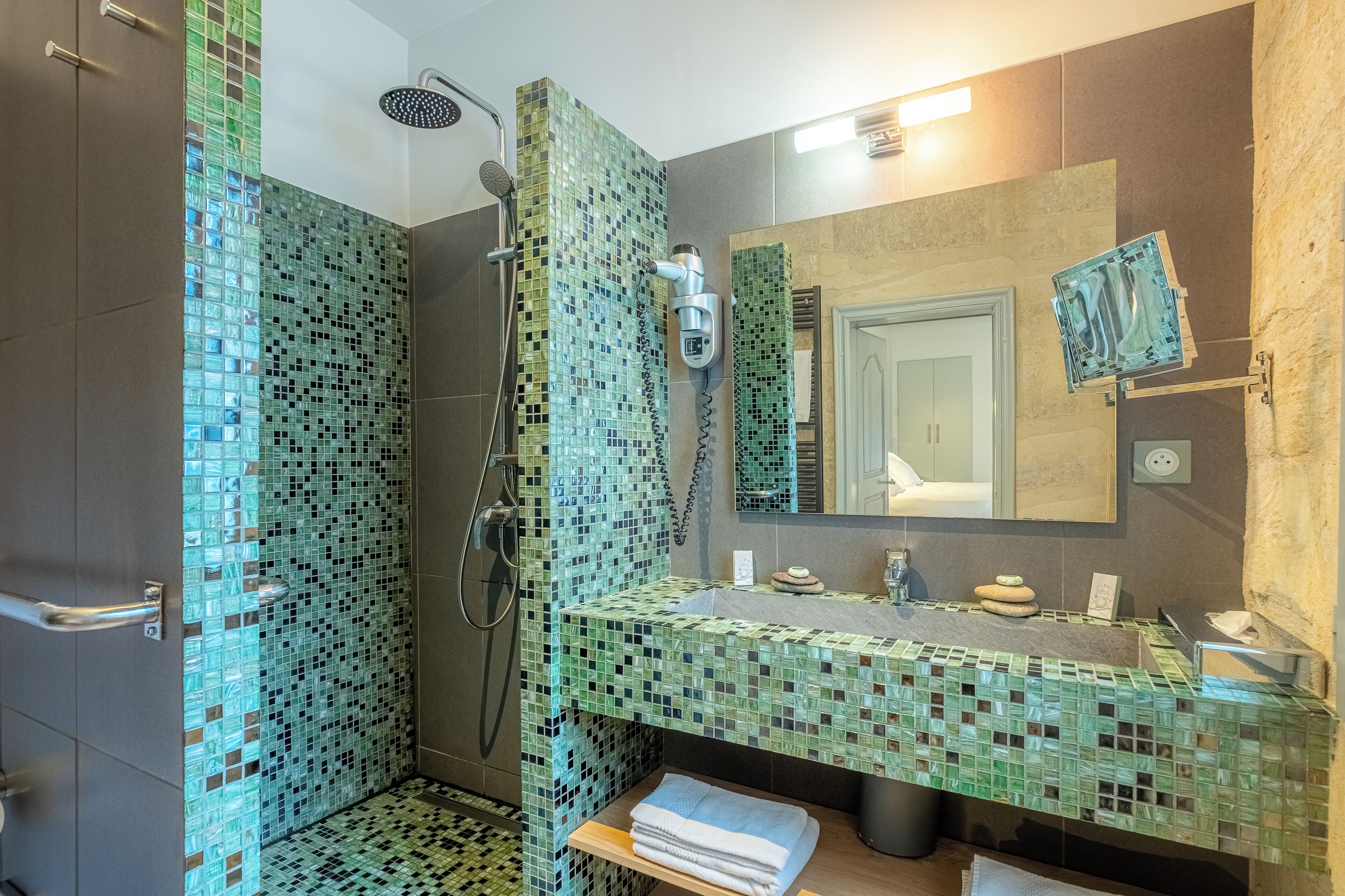 A bathroom with a shower, a sink with a mirror, and a towel rack.