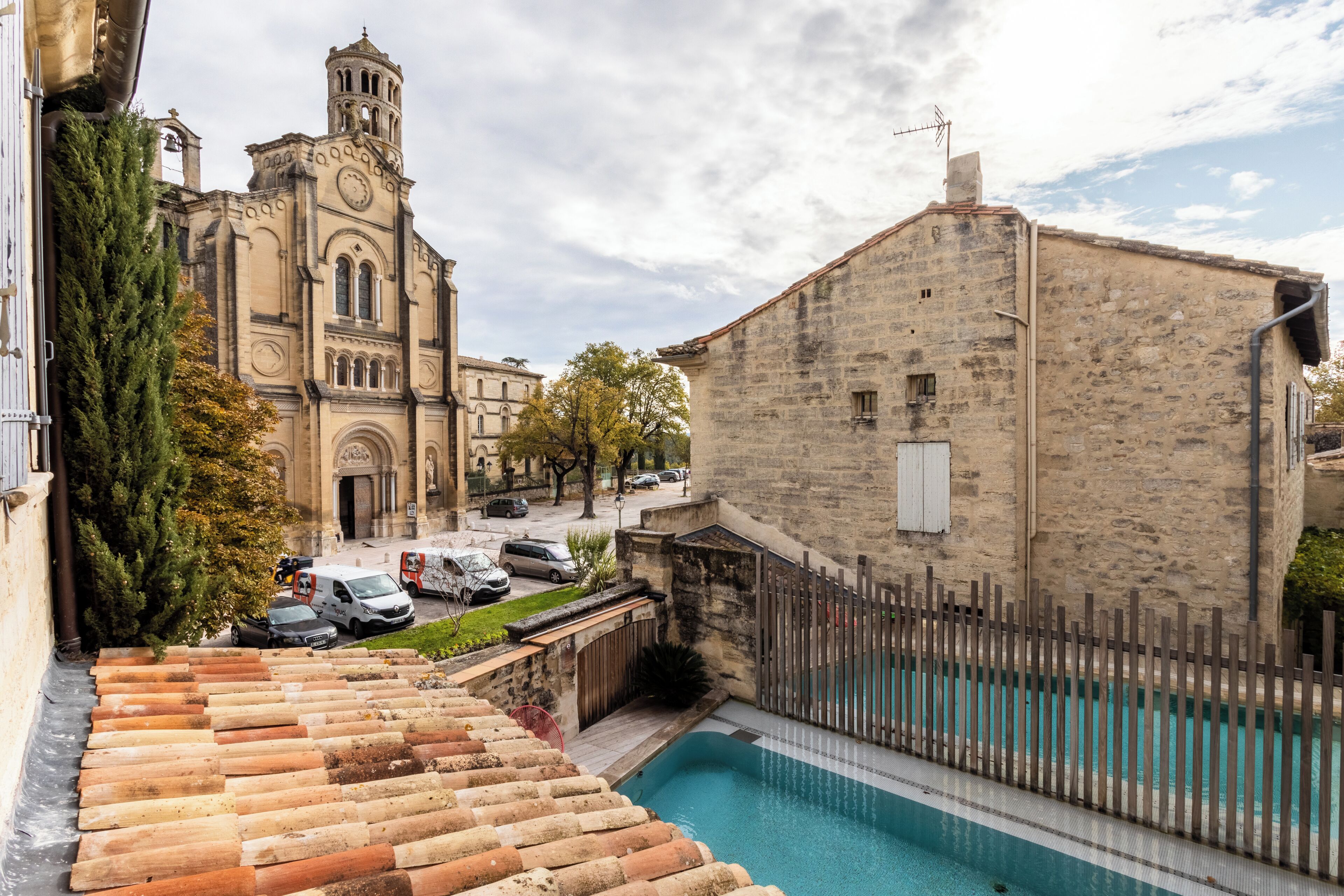 Une cour avec une piscine, une église et des bâtiments en pierre.