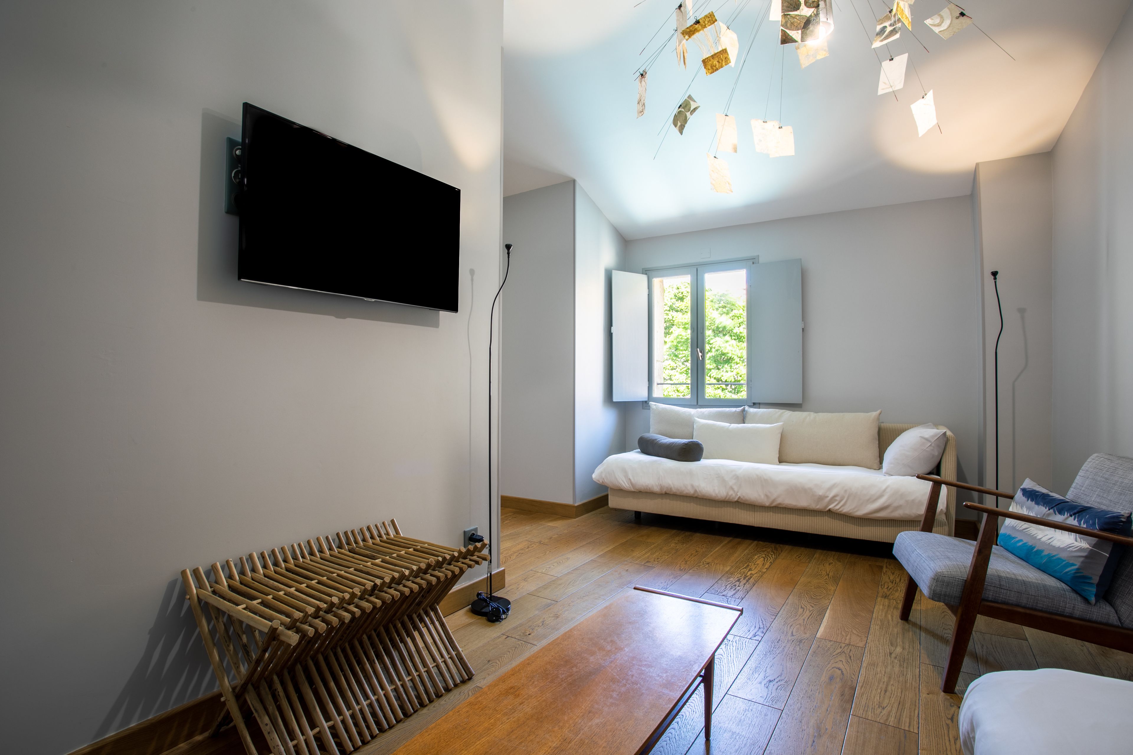 Een moderne woonkamer met een flatscreen televisie, een bank, een fauteuil en een houten vloer.