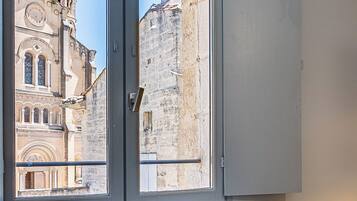 A room with a window overlooking a historic building with a bell tower.