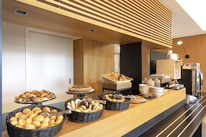 A buffet area with various baked goods and pastries displayed in baskets and on serving platters. - B&B Hotel Udine (Udine)