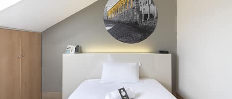 A hotel room with a neatly made bed, a round wall decoration, and a wooden wardrobe.