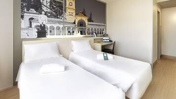 Habitación de hotel con dos camas individuales, un escritorio y un gran mural en la pared de un edificio histórico.