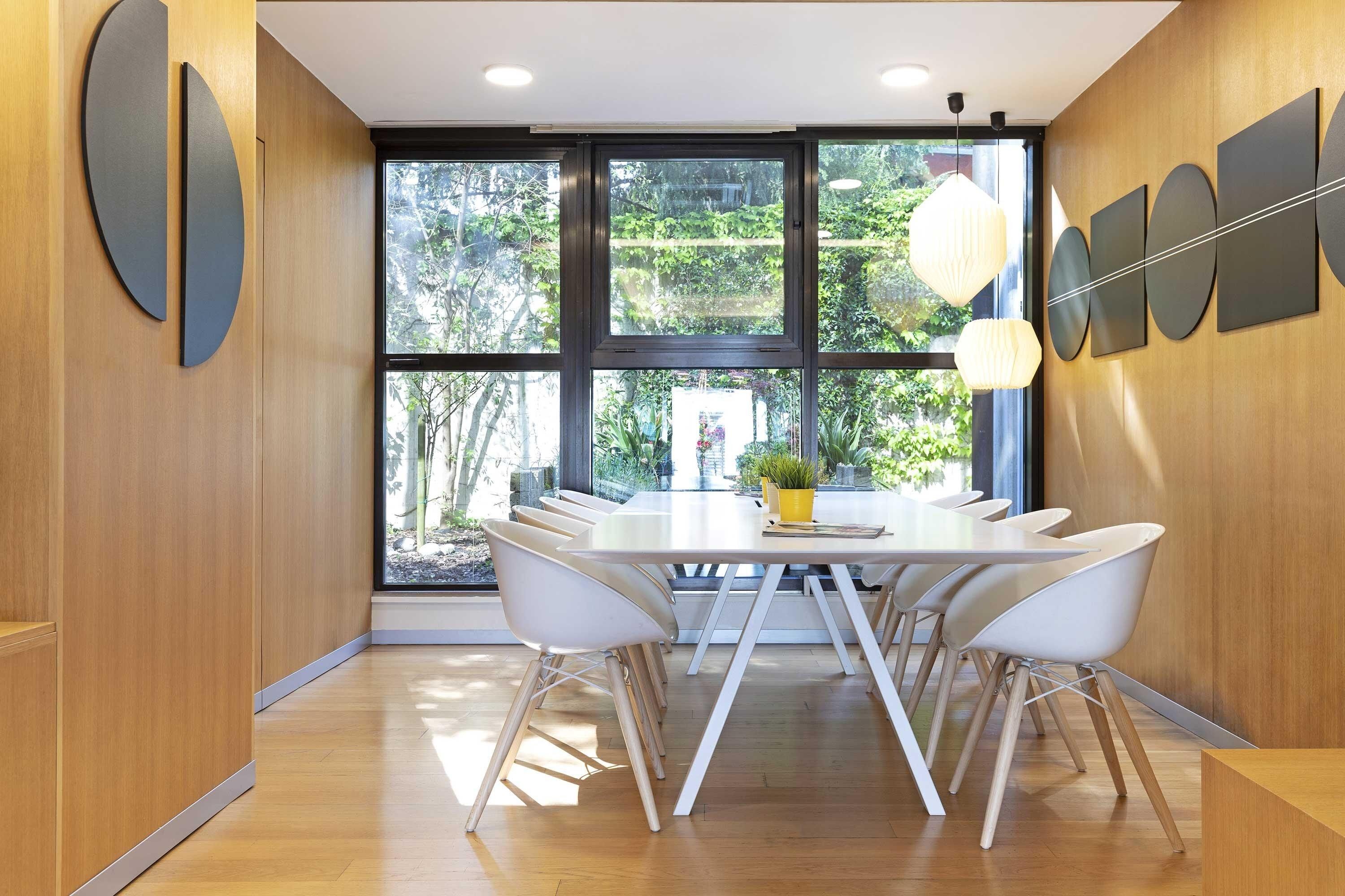 A modern dining area with a large window, a table with chairs, and a potted plant.