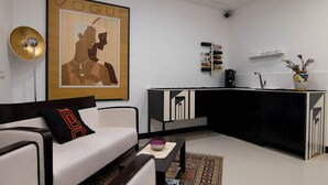 A modern living room with a white sofa, a black and white cabinet, and a large framed artwork on the wall. - Hotel Plebiscito Aparthotel (Naples)