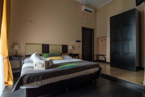 A hotel room with a large bed, bedside tables, an air conditioning unit, a wardrobe, and a door. - Hotel Plebiscito Aparthotel (Naples)